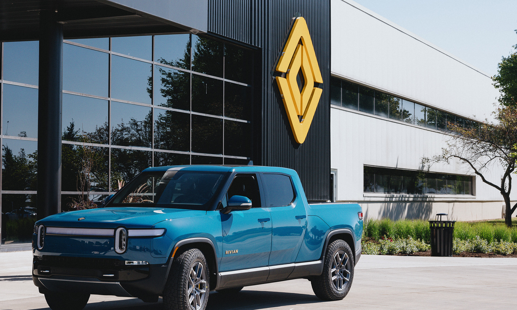 Rivian truck in front of building with Rivian logo. Rivian truck in front of a building with a Rivian logo.