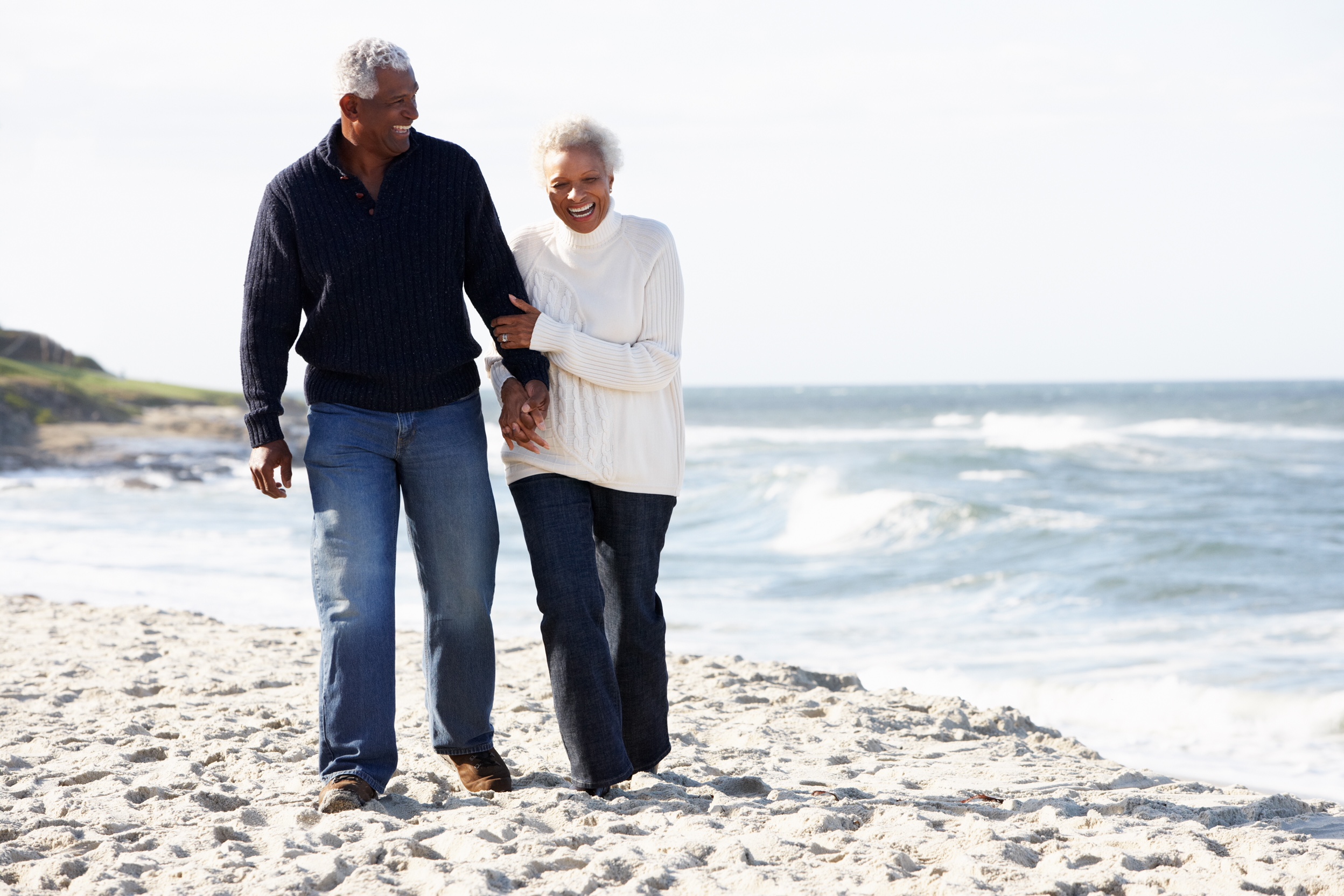 senior couple holding hands on beach