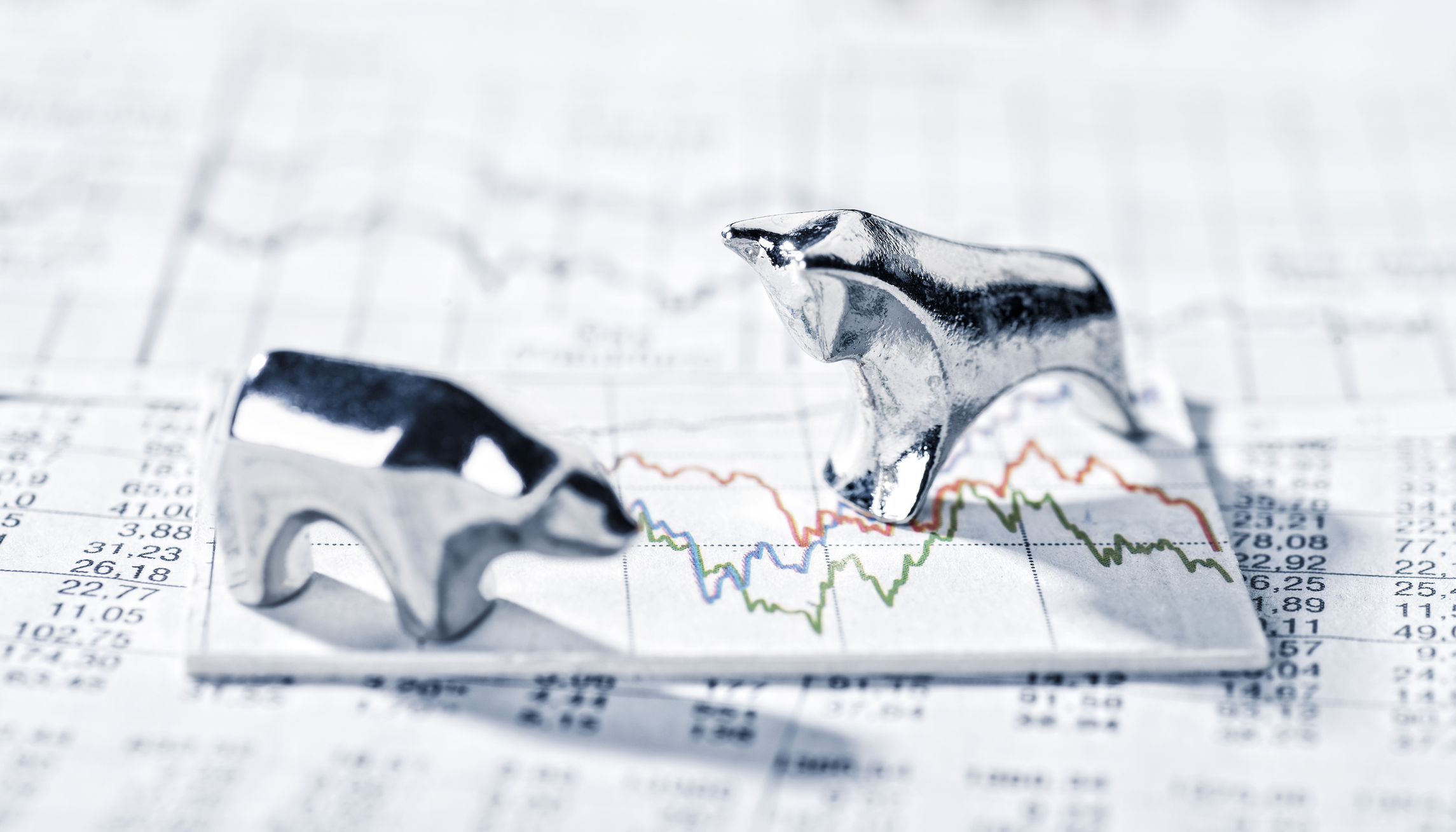 Bull and bear figurine standing on stock chart