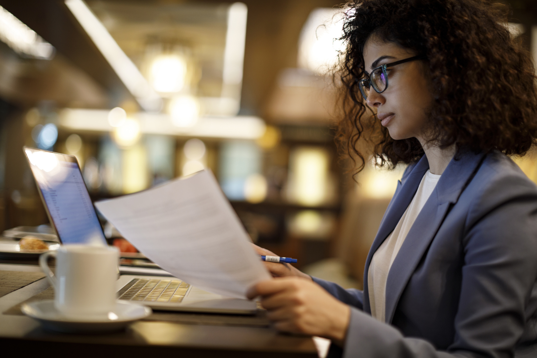 Woman sitting at computer while reviewing financial statements Person sitting at computer while reviewing financial statements.
