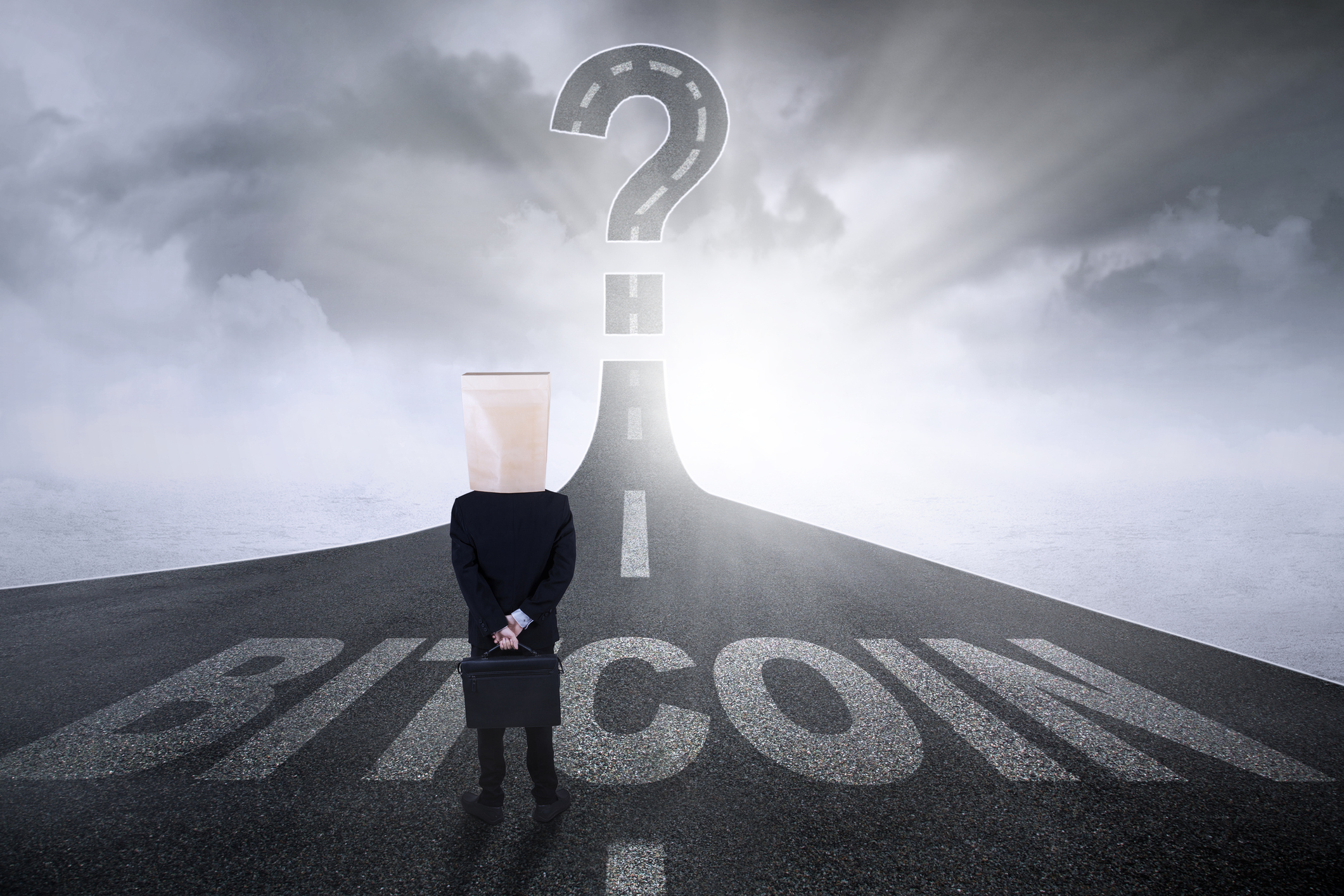 A road with the word bitcoin leads to a question mark in the sky. A person standing on a road with the word bitcoin written on it leading to a question mark in the sky.