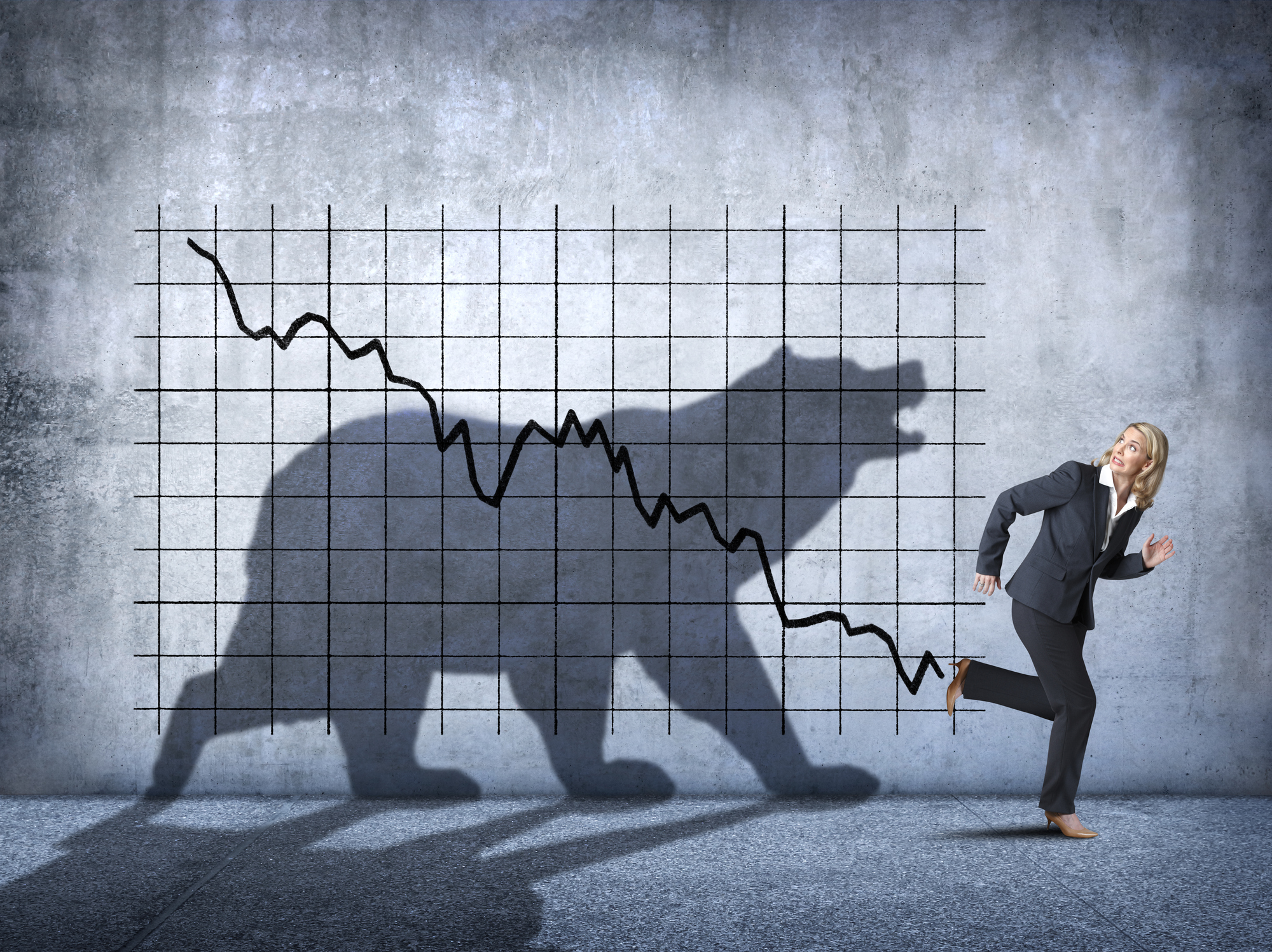 Investor running away from bear market. Person running away from shadow of bear on background of declining arrow on graph.