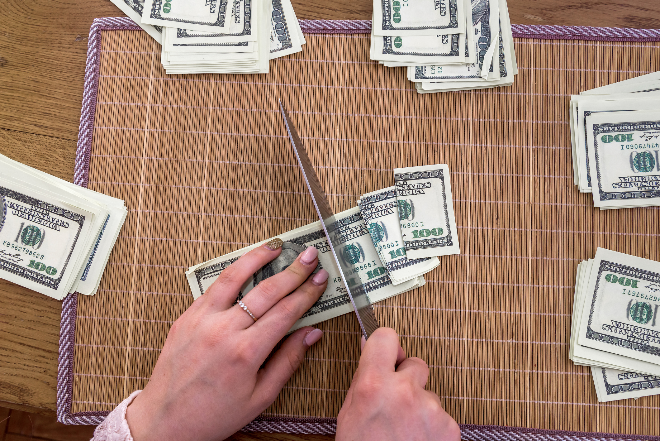 Person cutting dollars into pieces with a knife. Person cutting dollars into pieces with a knife.