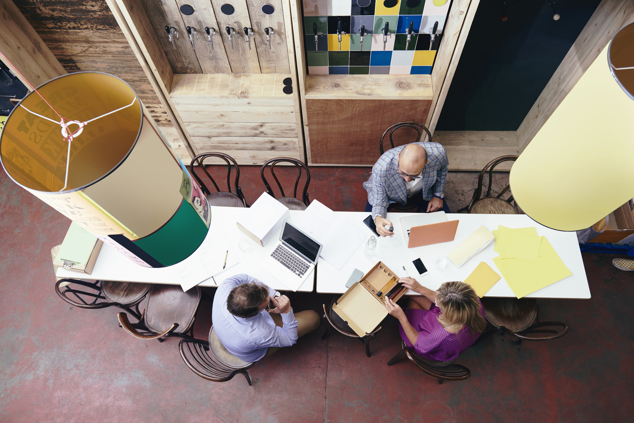 Employees sitting in office working at long table as seen from overhead Employees sitting in office working at long table as seen from overhead
