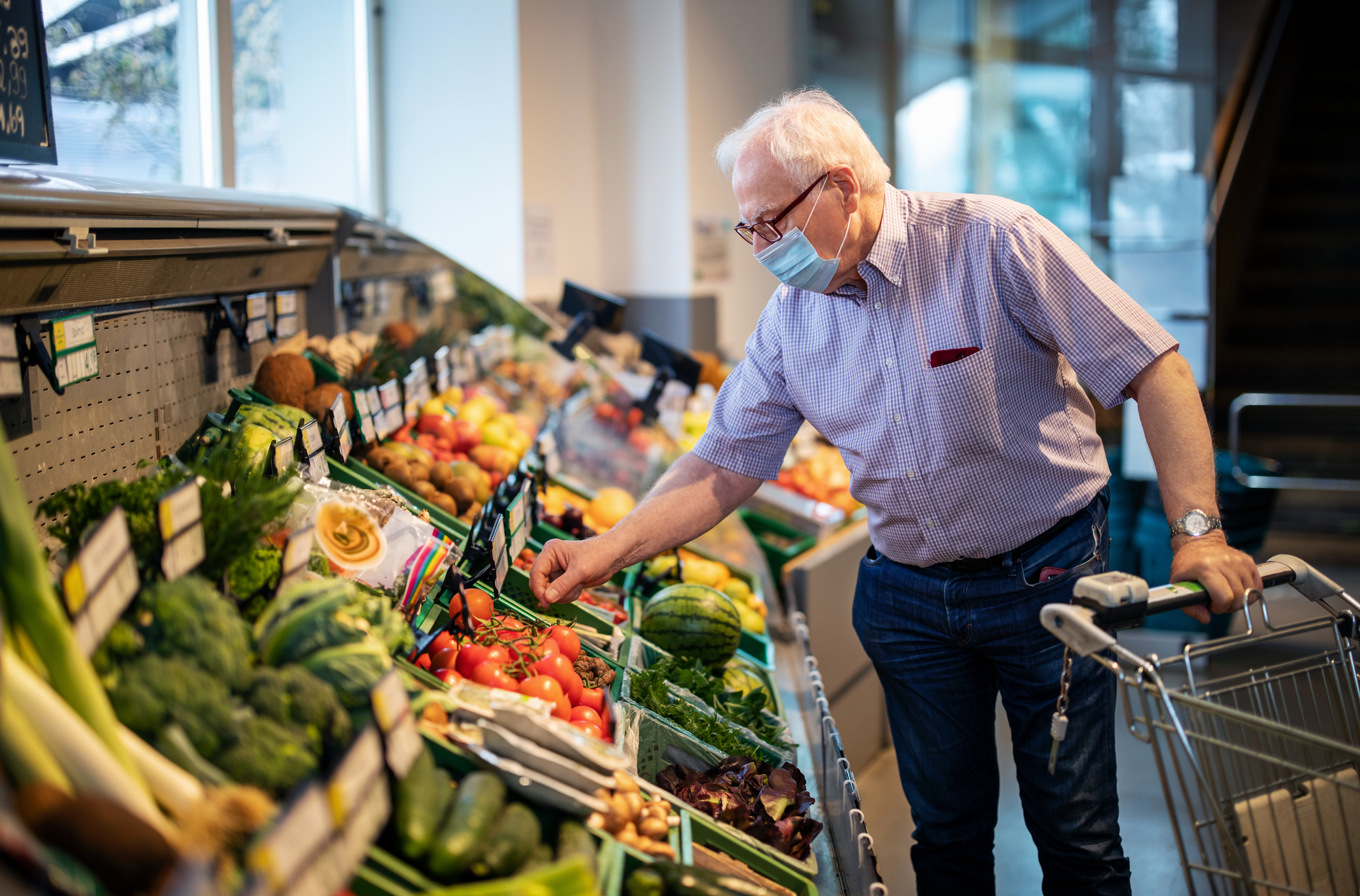 Masked person shopping for produce in grocery store. Masked person shopping for produce in grocery store.