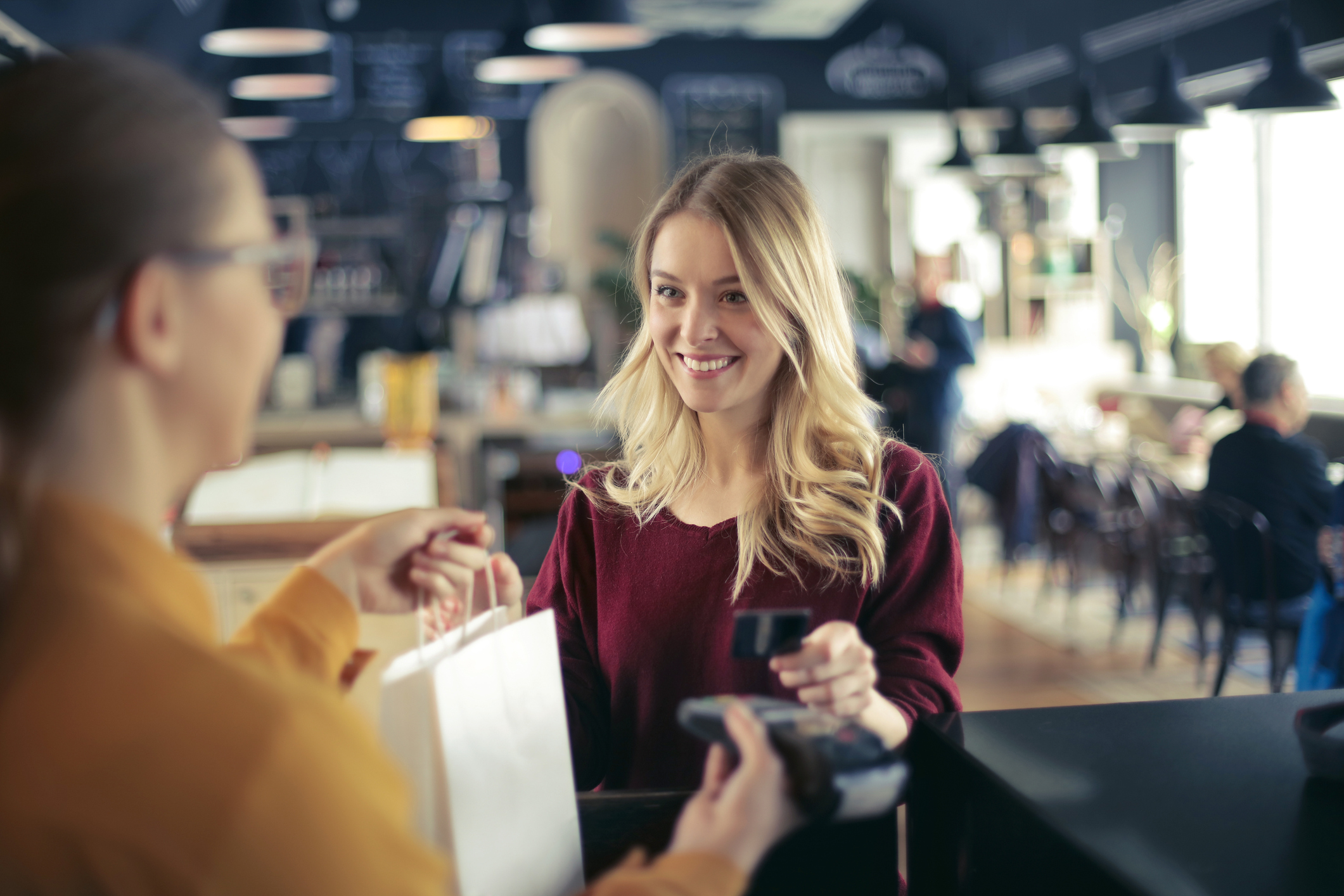Cashier handing a woman a small bag in exchange for her credit card.