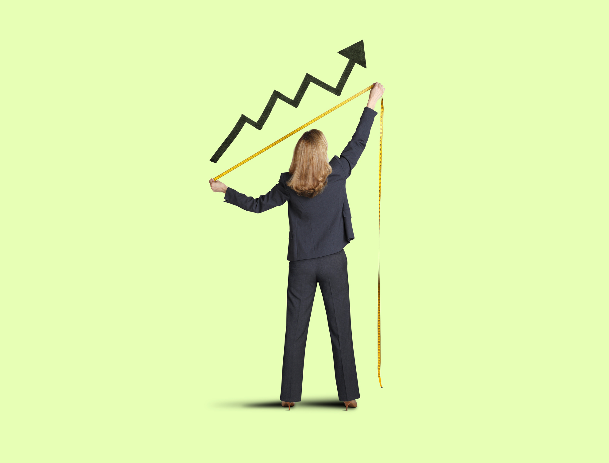 Businesswoman in suit is using yellow measuring tape to measure growth of black upward arrow against green background. Businessperson is using yellow measuring tape to measure growth of black upward arrow against green background.