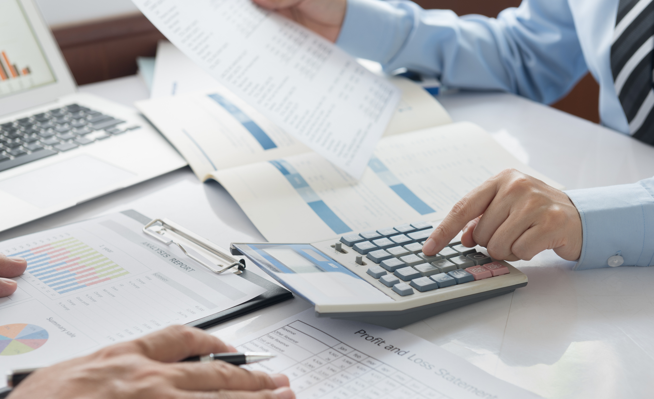 Person using calculator while looking over accounting spreadsheets Person using calculator while looking over accounting spreadsheets.