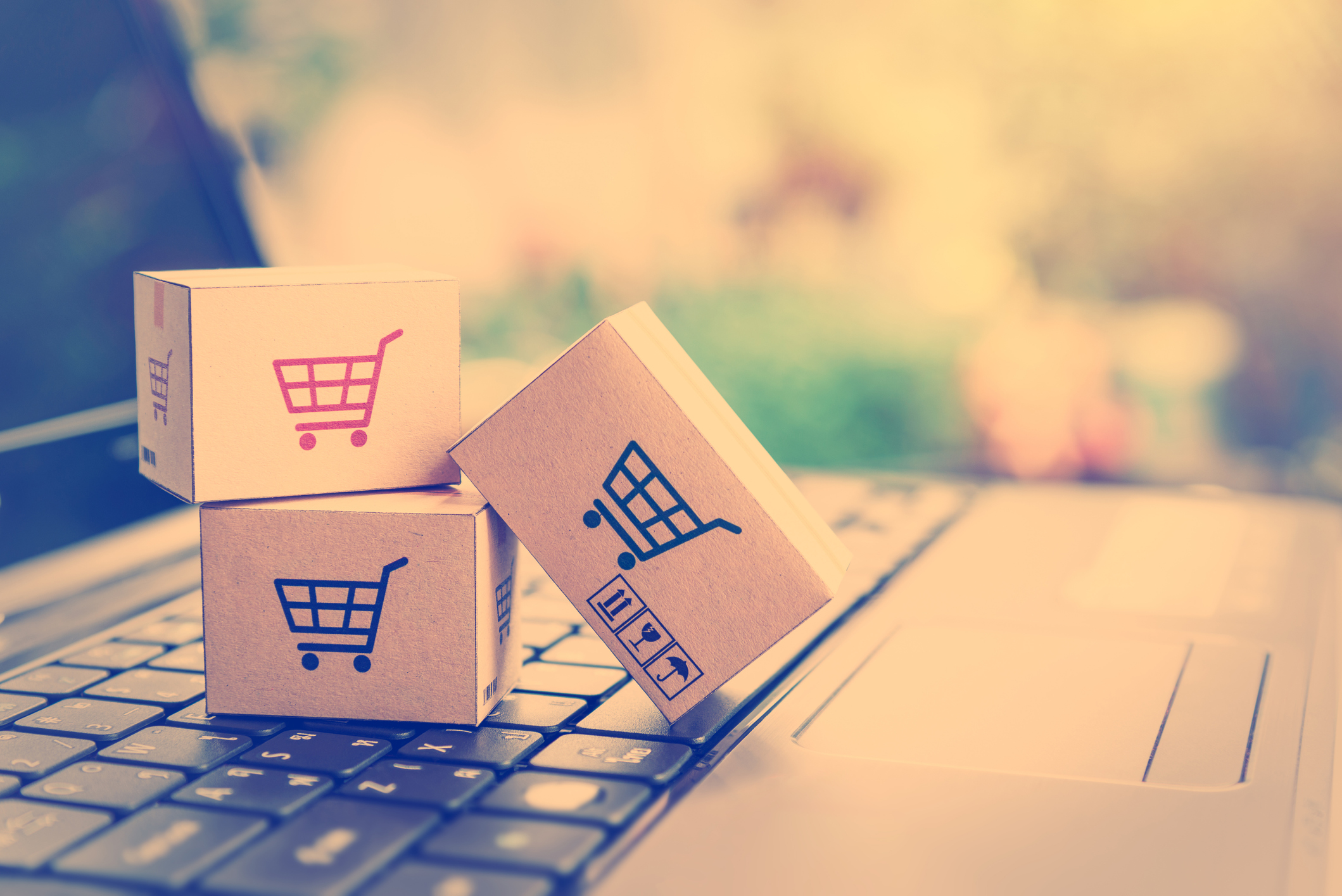 e-commerce Small boxes with shopping cart logos sitting on laptop keyboard.