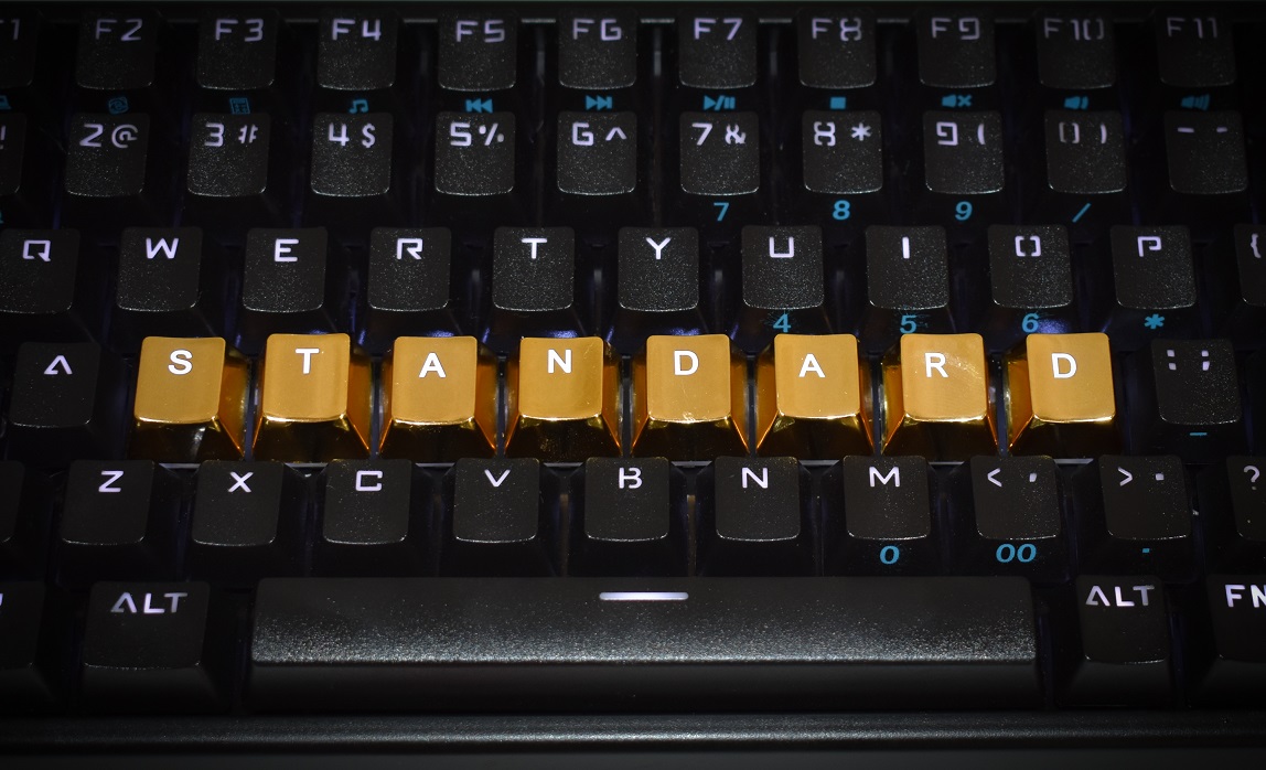 Keyboard with letters rearranged spelling out "STANDARD" in gold letters. Keyboard with keys rearranged to spell Standard.