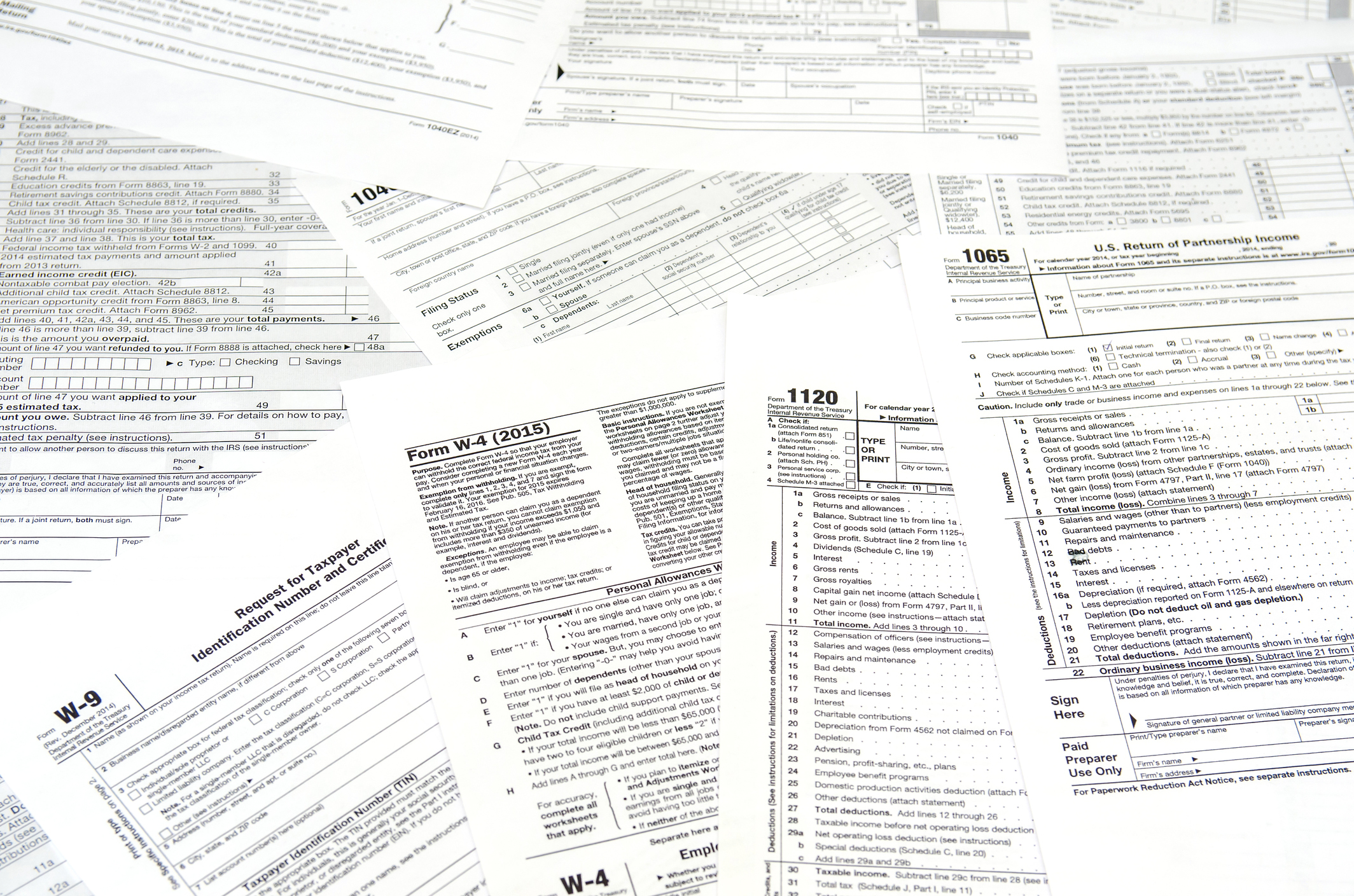 A pile of scattered tax forms that includes a W-9 and W-4.