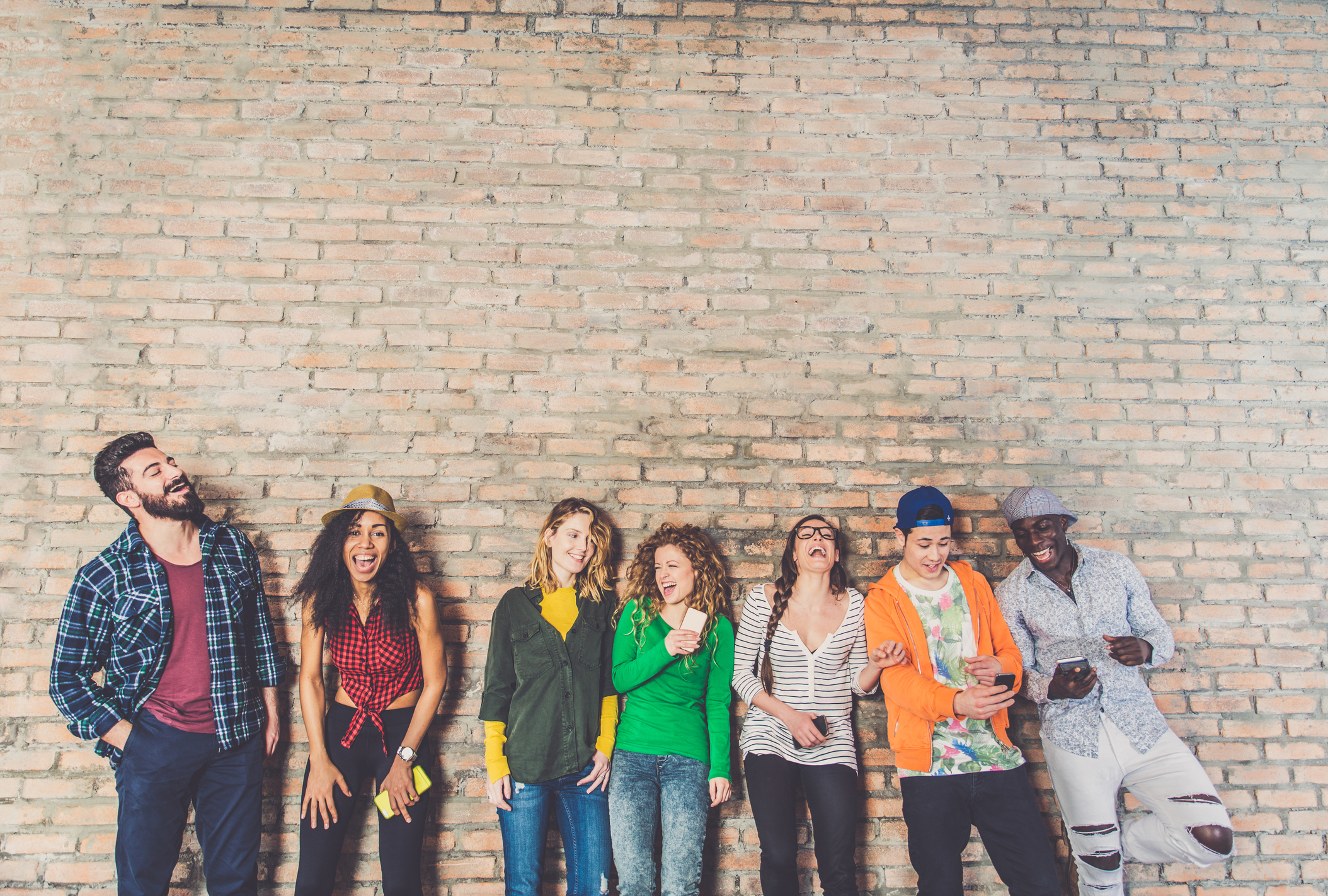 Group of teenagers hanging out by a brick wall. Group of teenagers hanging out by a brick wall.