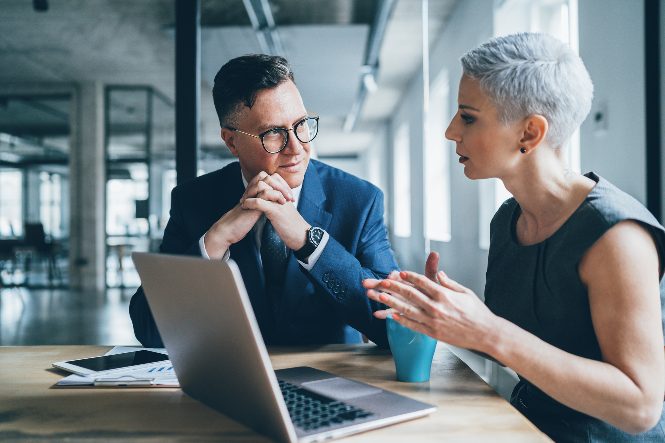 Two businesspeople talking in front of laptop Two businesspeople talking in front of a laptop.