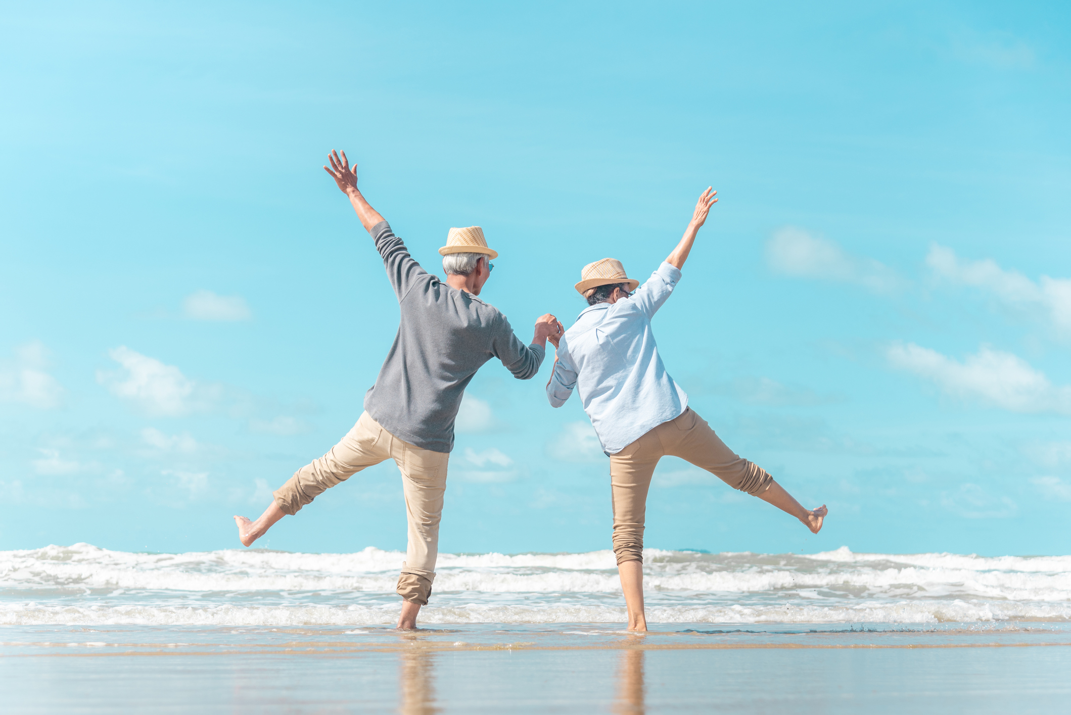 Two older men on beach holding hands with arms in the air.jpg Two older men on beach holding hands with arms in the air