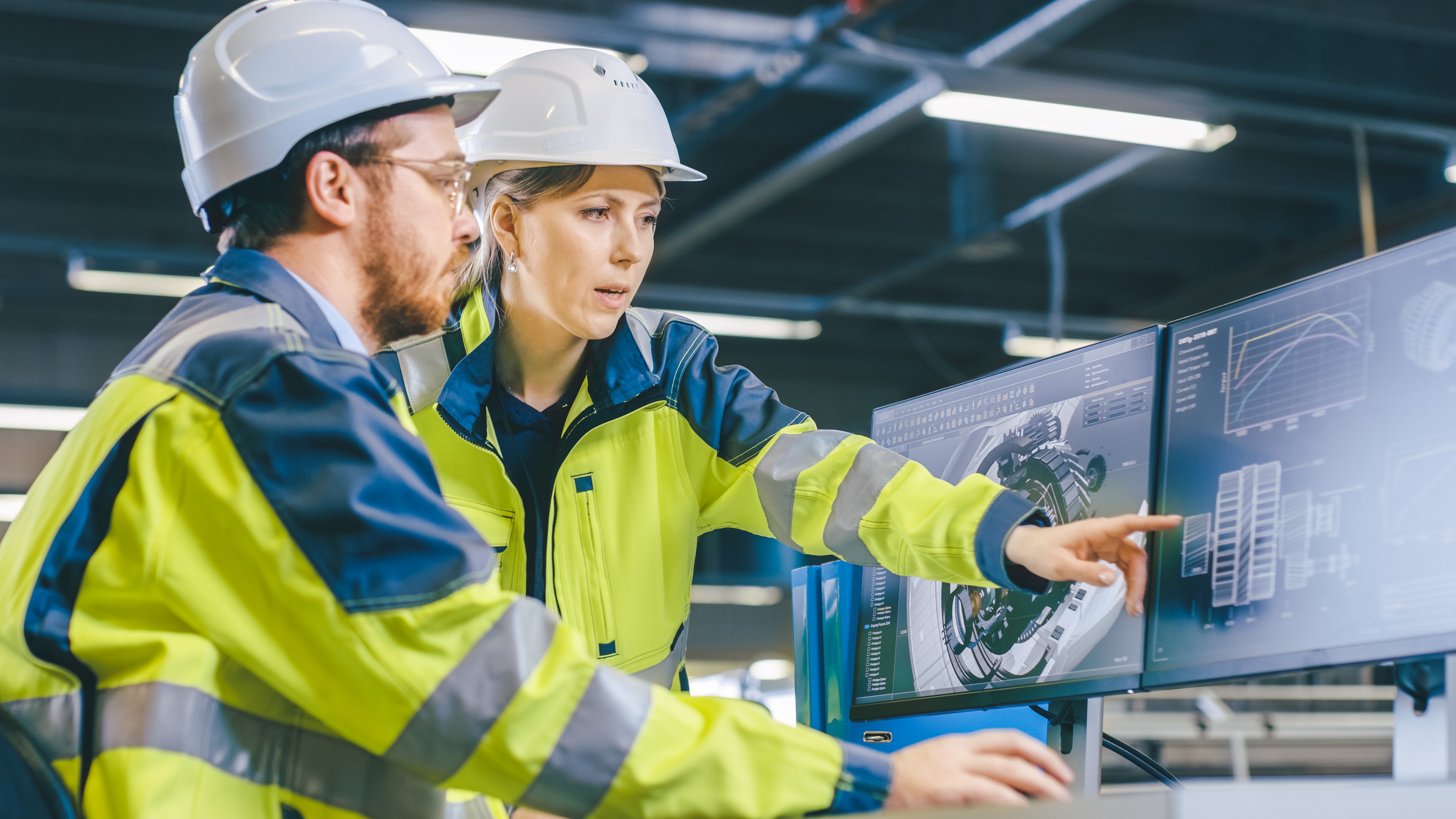 construction worker showing colleague blueprints.jpg One construction worker points at blueprints on a computer screen while a colleague looks on.