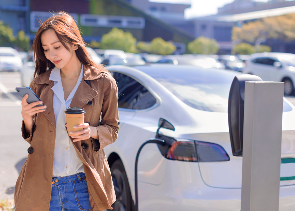 A driver waits for an electric vehicle to charge. A driver waits for an electric vehicle to charge.