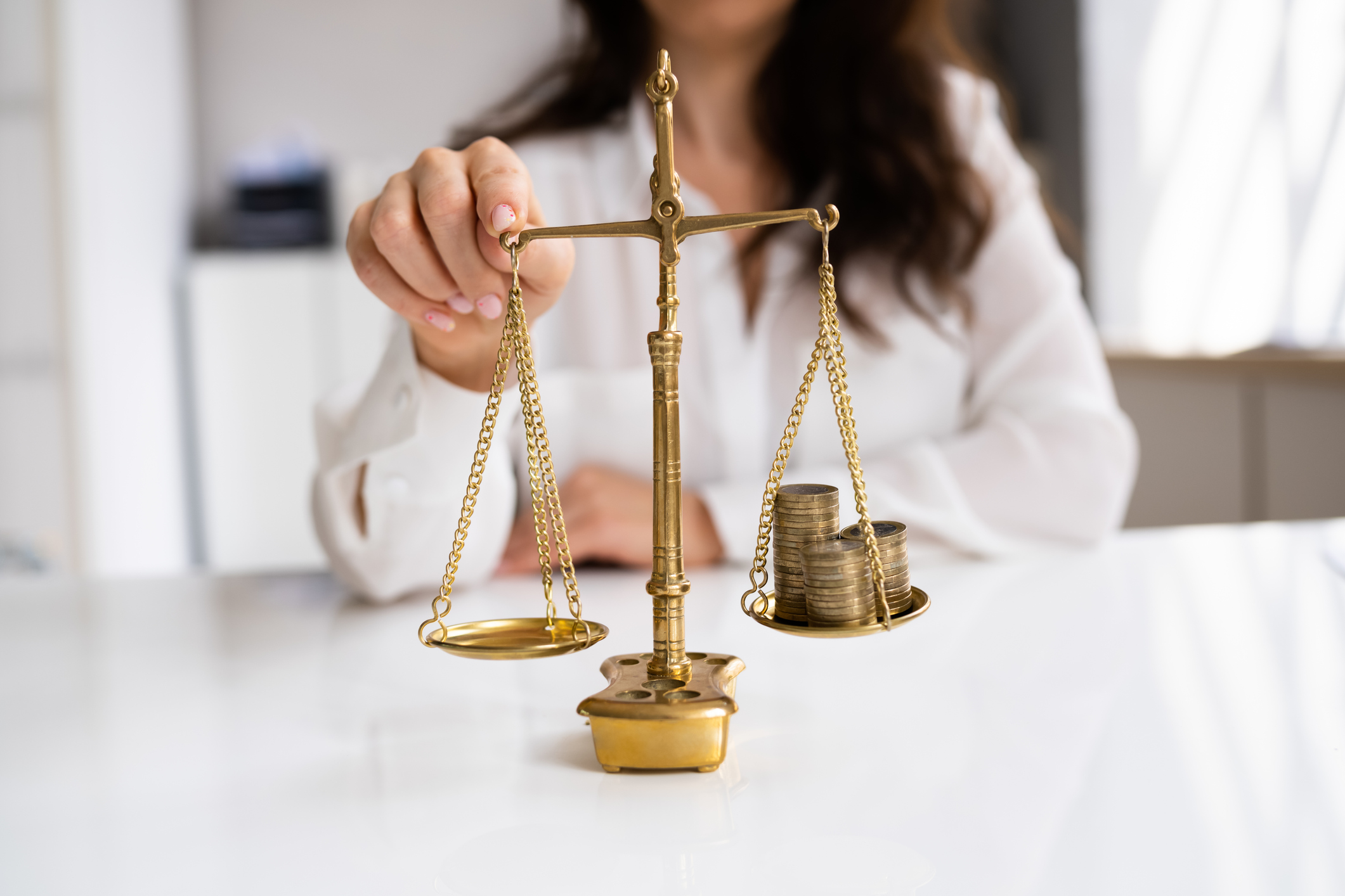 Balancing money on golden scales A person weighs coins on a golden scale, tipping the balance with one finger.