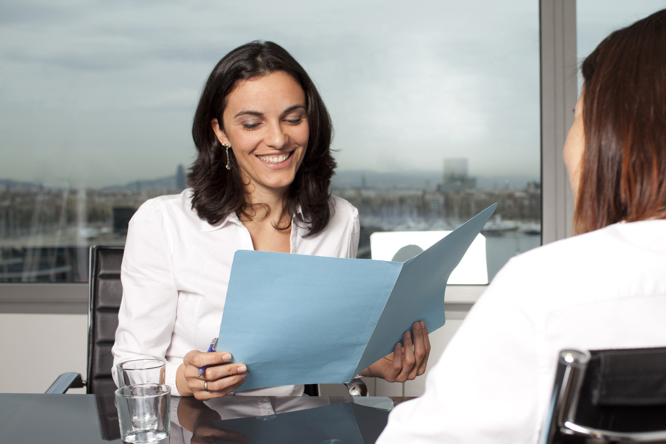 Two people in a meeting Two people in a meeting, with one looking at some papers in a file folder.