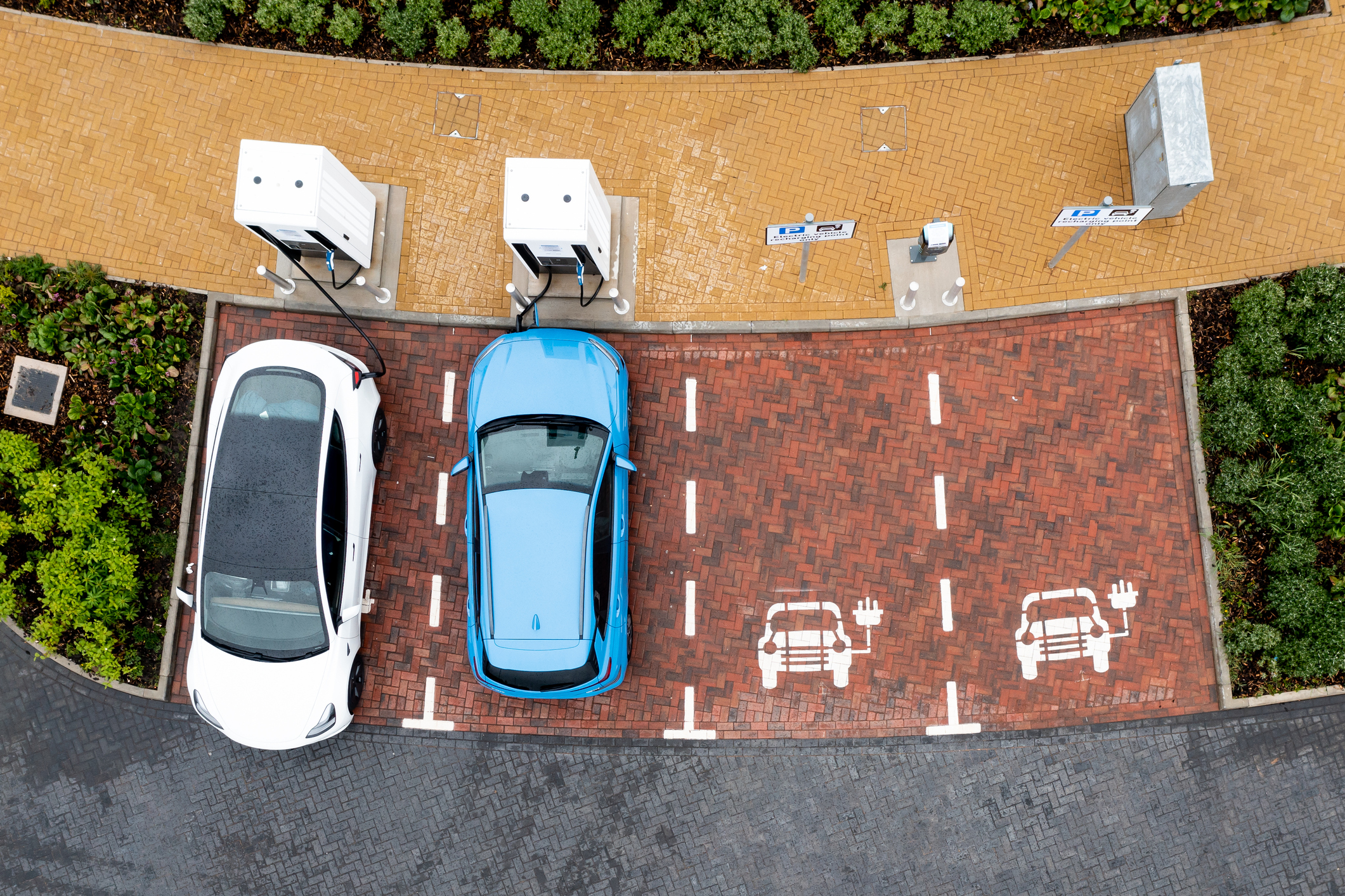 cars at EV charging stations Overhead shot of two electric cars at EV charging stations.