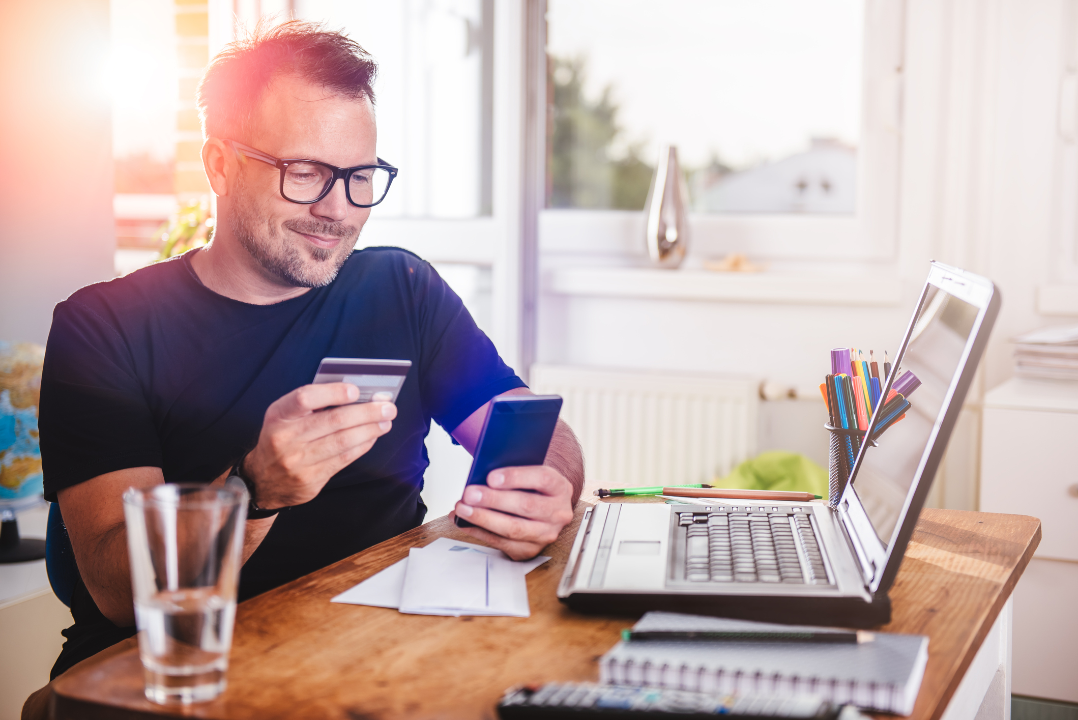 Credit Card 6 A person is holding a credit card and smartphone while sitting in front of a laptop.