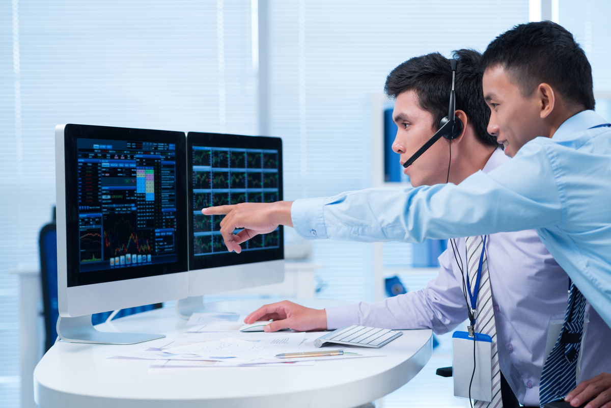 Two traders looking at stocks on computer screens