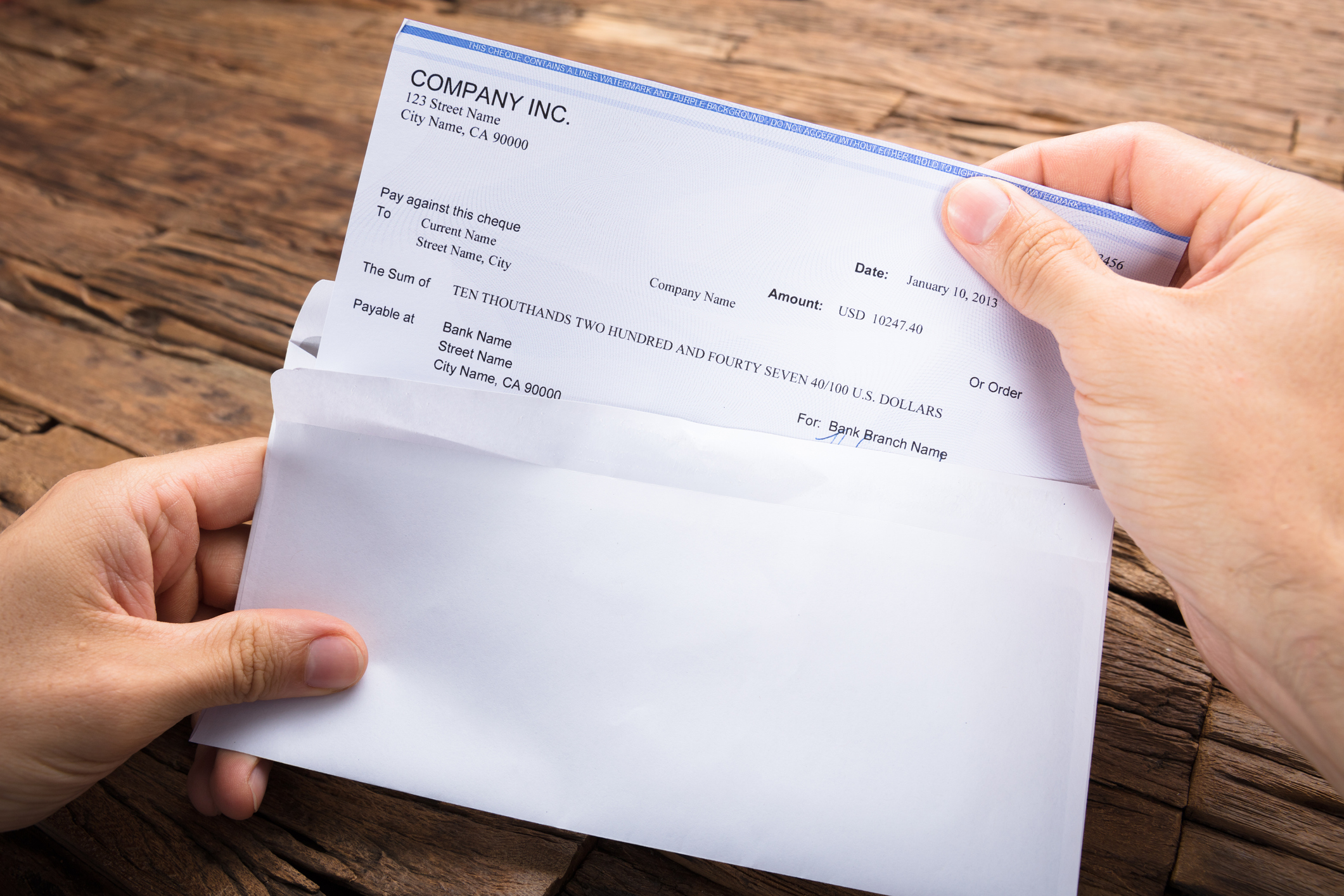 Hands pulling a paycheck out of an envelope Hands pulling a paycheck out of an envelope.