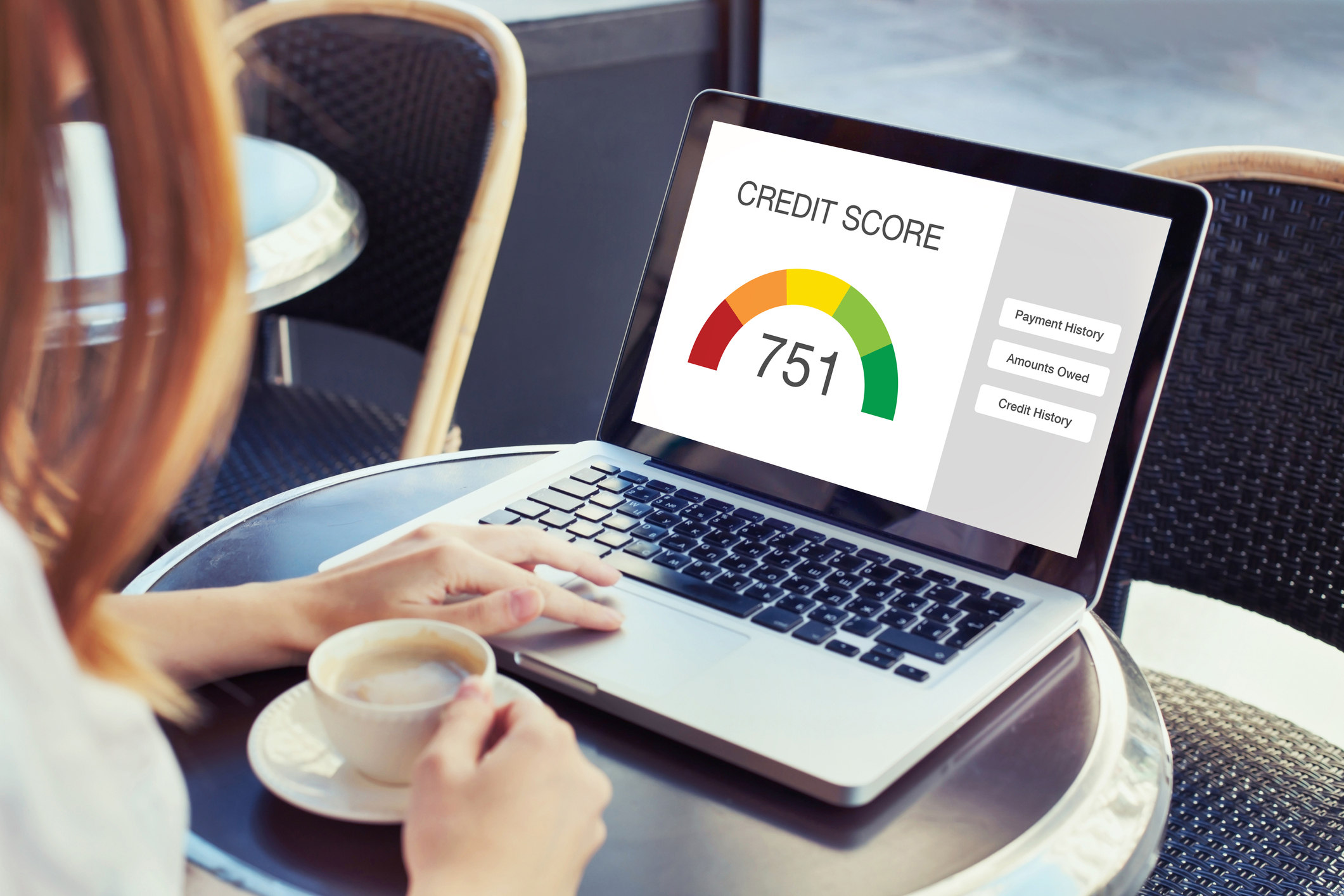credit score on laptop and person with coffee.jpg Person with coffee cup and laptop with credit score showing.