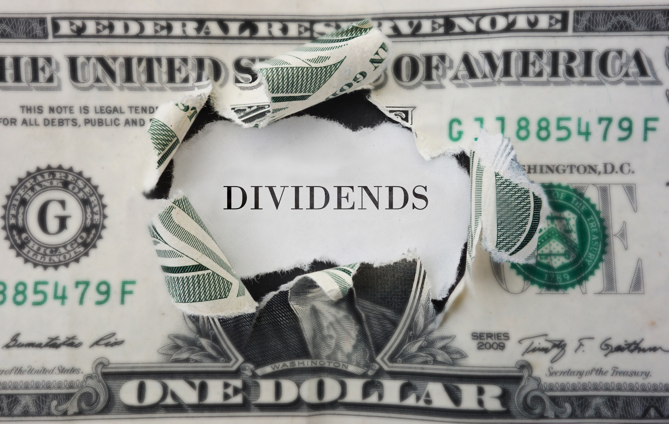 The word Dividends inside dollar bill The word Dividends inside a torn-open dollar bill.