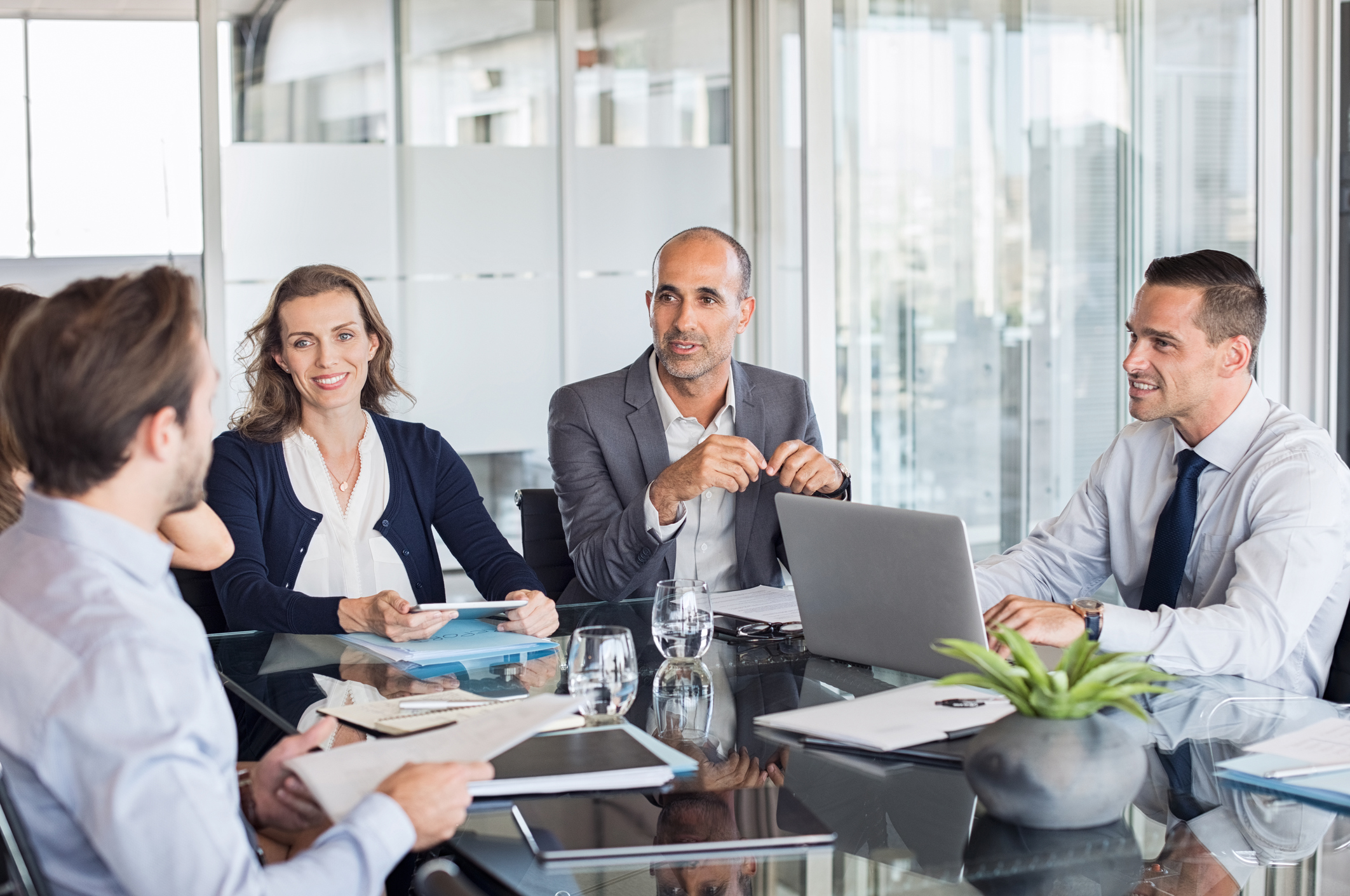 A group of professionals around a table at a meeting. A group of professionals around a table at a meeting.