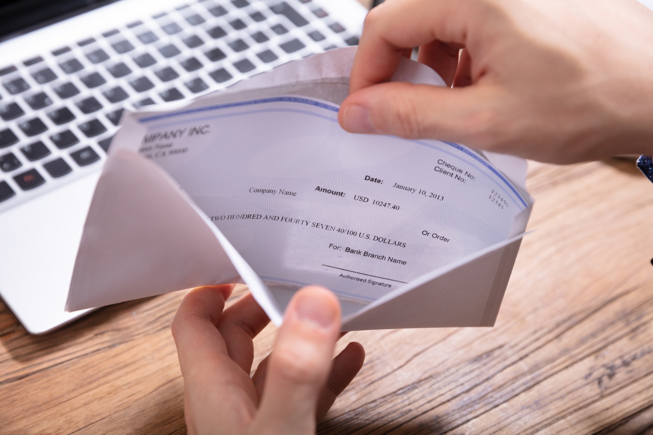 hands opening a check in an envelope.jpg Hands opening check in envelope