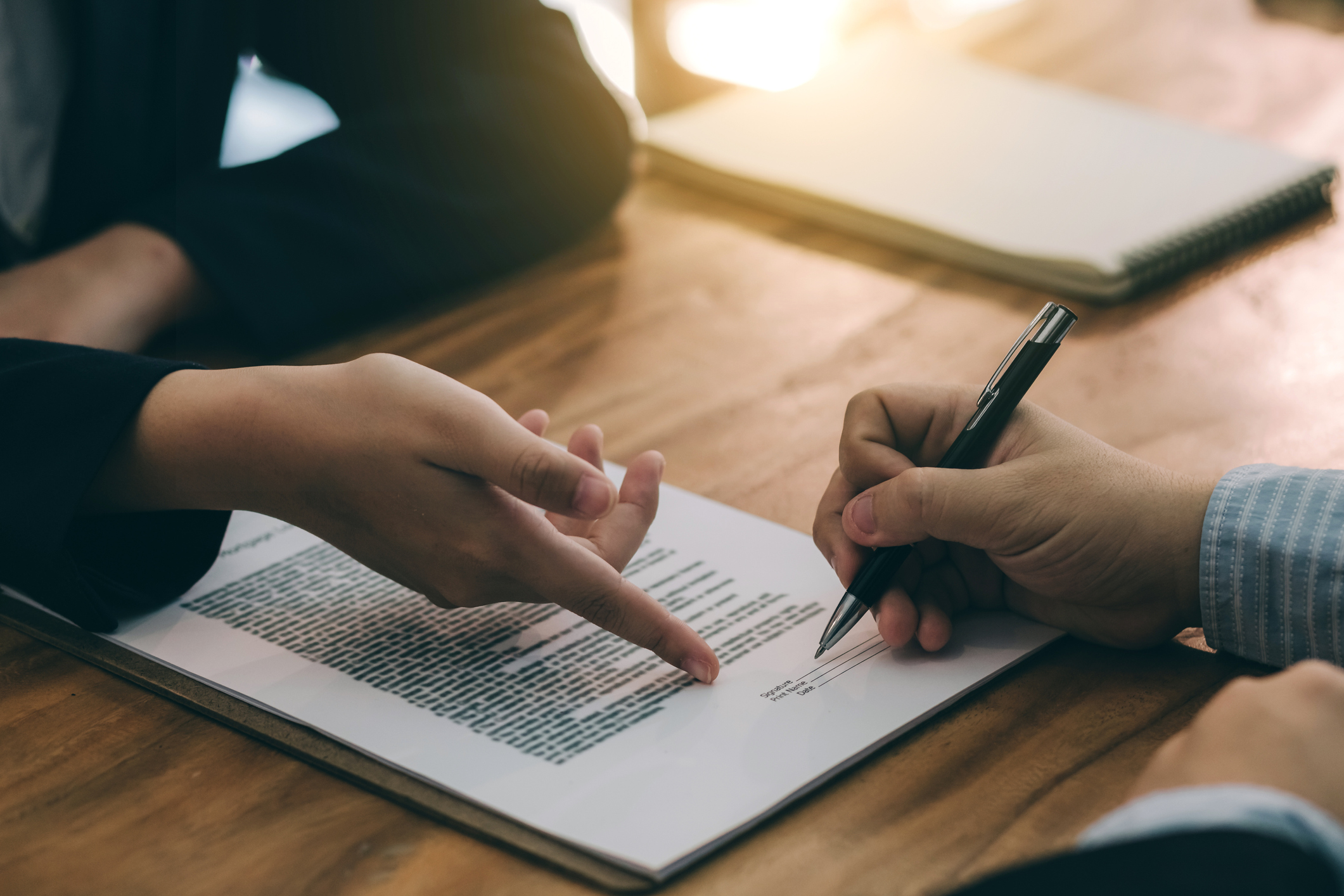 Two pairs of hands engaged in signing a contract.