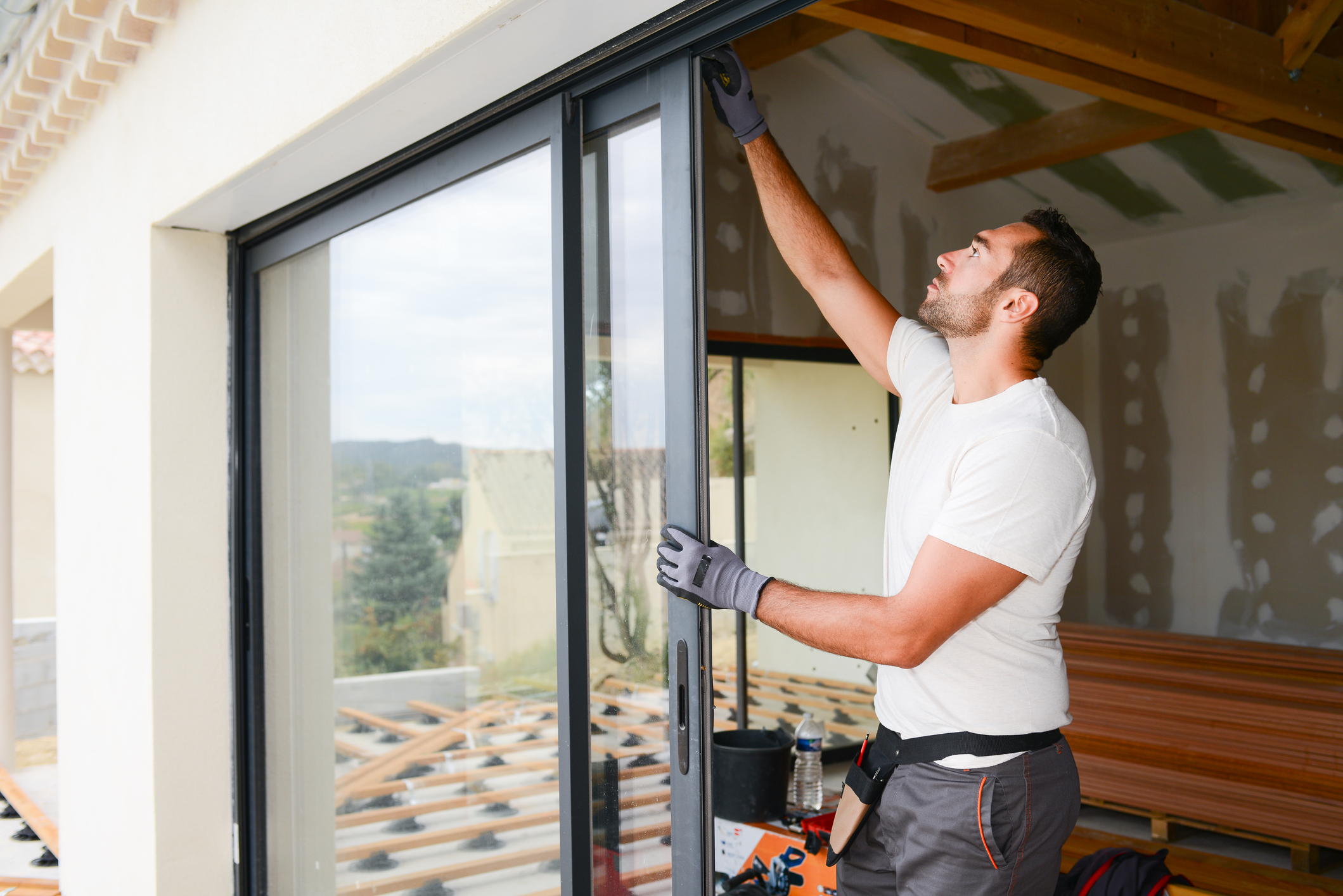 young man installing bay window in a new house construction site Person installing bay window in a new house construction site.