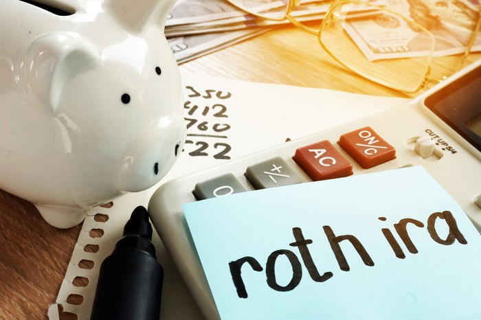 Piggy bank next to Roth IRA on notepad. Piggy bank next to Roth IRA on notepad.