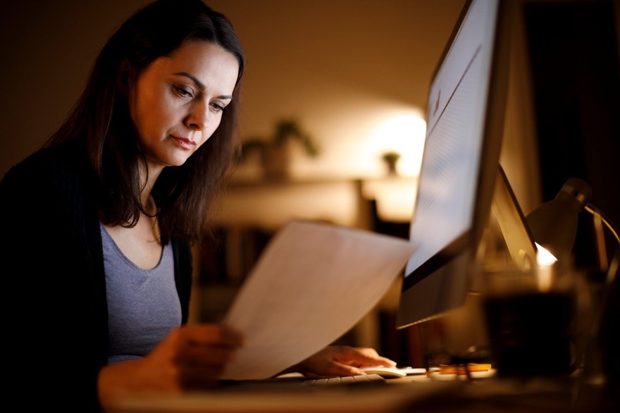 Woman researching self-directed IRA providers at home at night. Woman researching self-directed IRA providers at home at night.