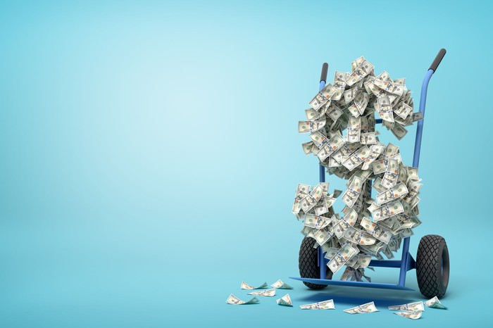 A hand truck moving a large dollar sign shape made of floating dollar bills. A hand truck moving a large dollar sign shape made of floating dollar bills.