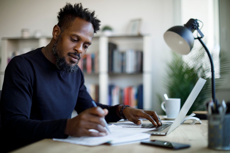 Middle-aged man looks at papers on desk Middle-aged man looks at papers on desk