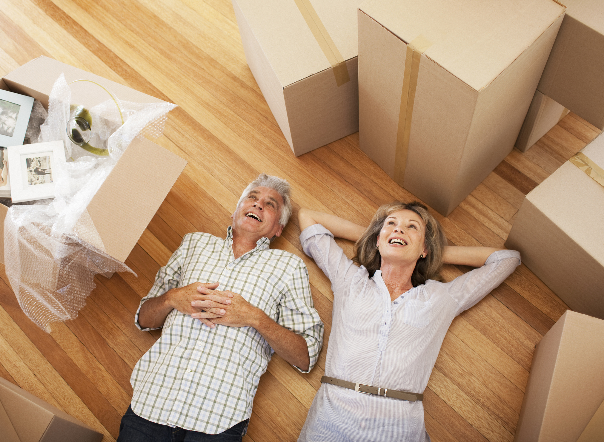Mature couple lying on floor among boxes taking break during move