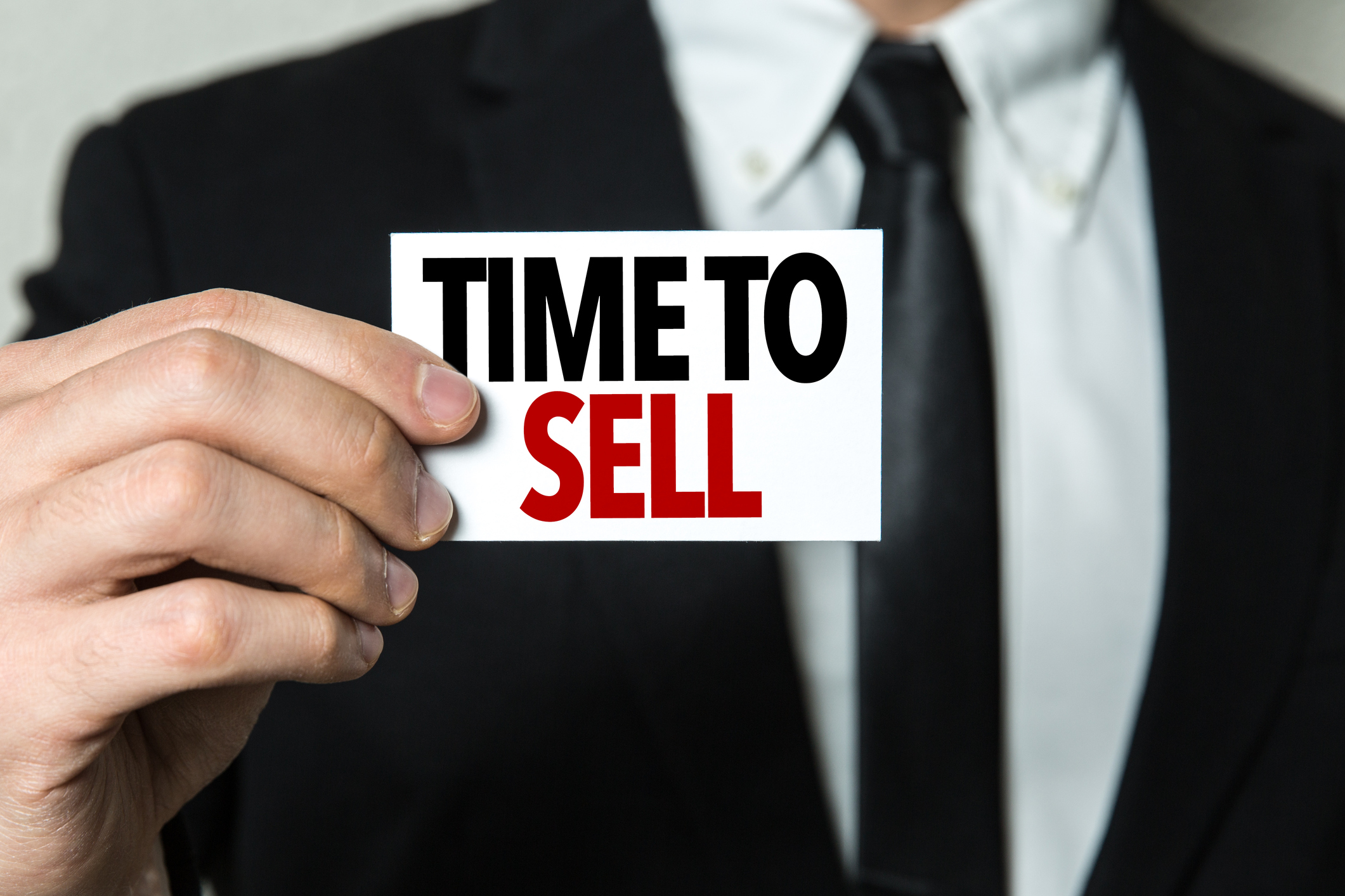 person in business suit holding sign that says time to sell -- investment capital loss stock Person in business suit holding sign that says Time to Sell.