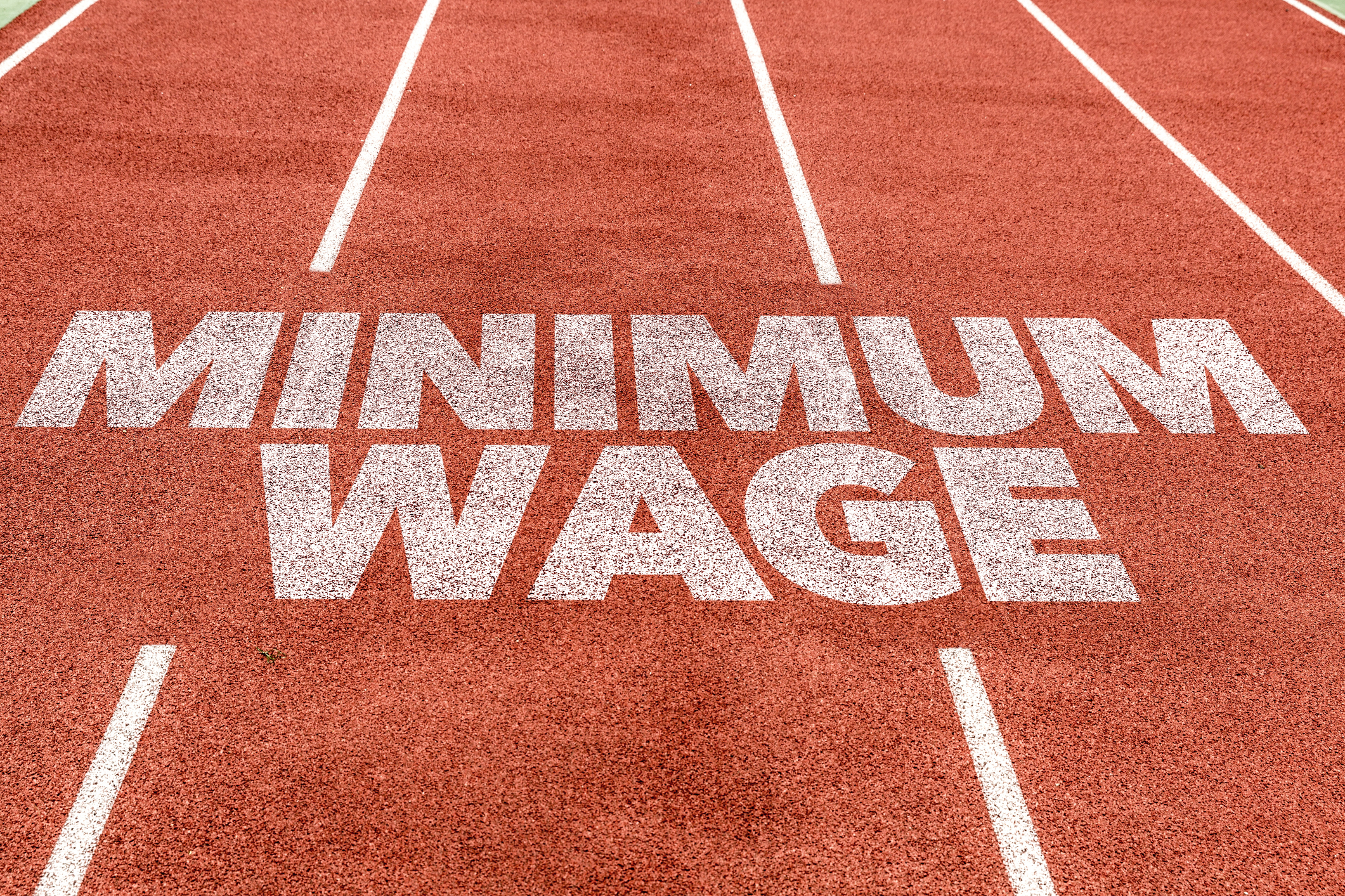 Minimum wage in white paint on a red track field.