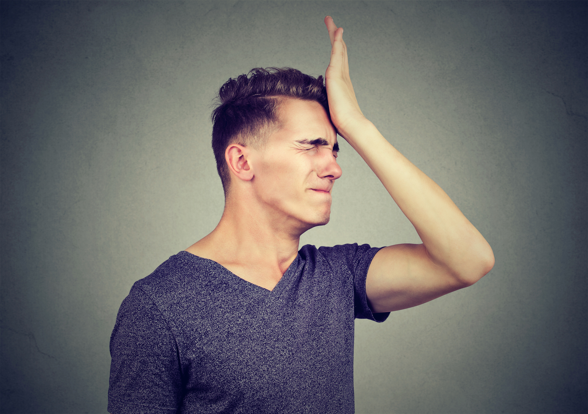 Young man with palm to head as if frustrated with himself.