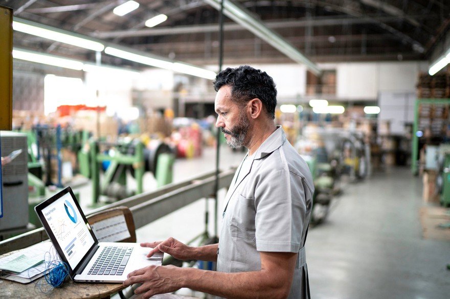 A man in a factory works on new capital purchases. A man in a factory works on new capital purchases.