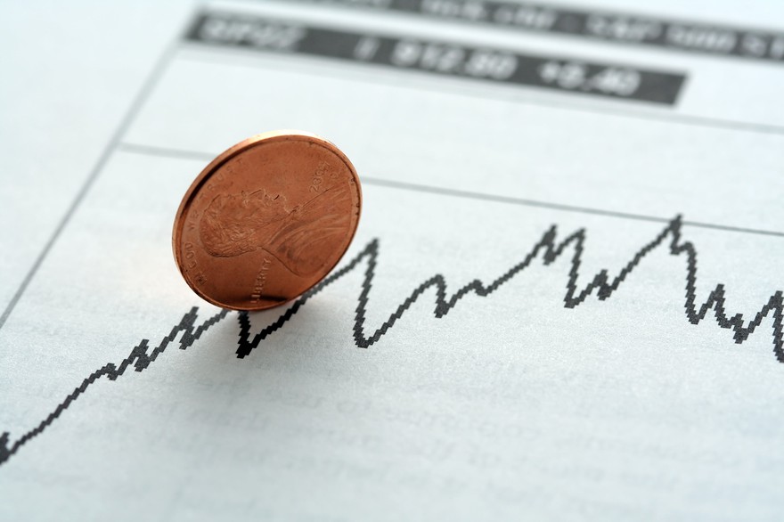 A penny on edge, on top of a stock chart A penny on edge, on top of a stock chart