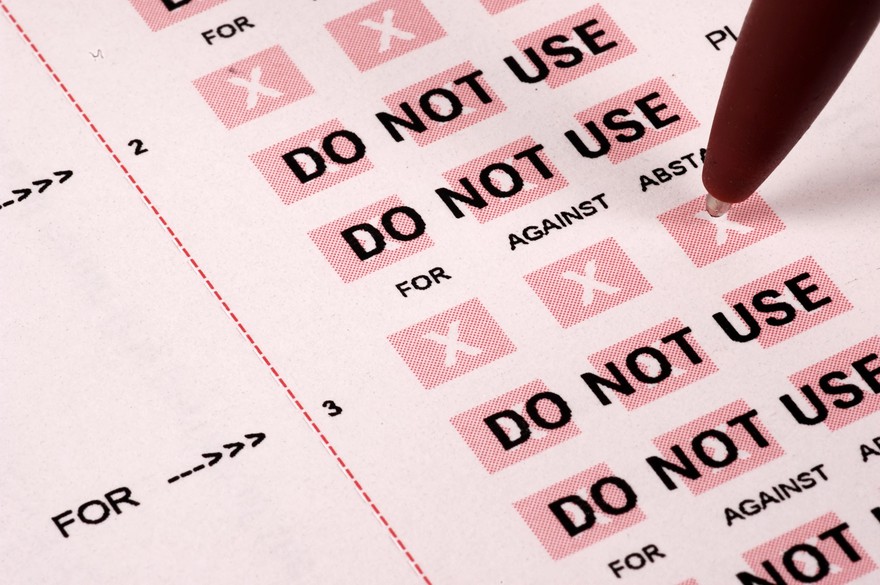 Close up of someone marking a ballot with a pen.