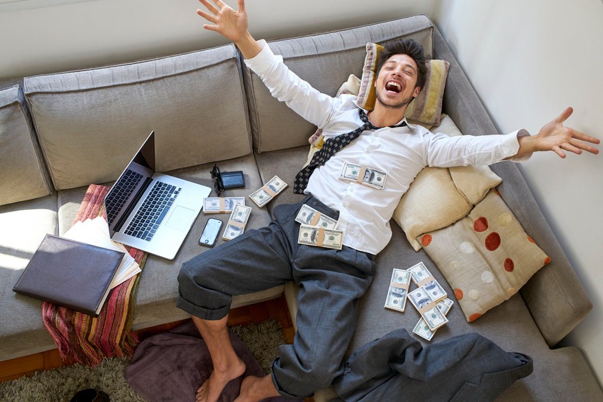 A man lying on a couch covered in cash A man lying on a couch covered in cash