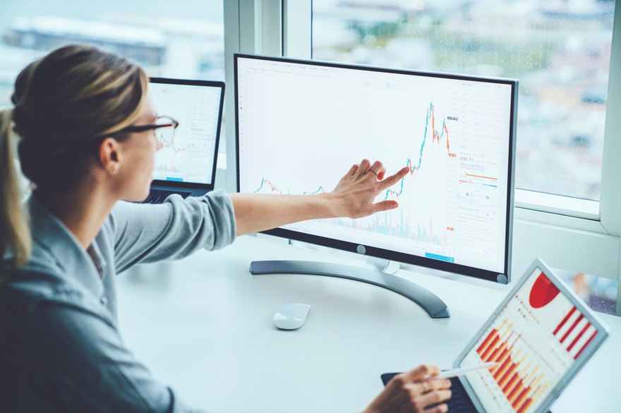 Woman looking at a stock chart on a monitor. Woman looking at a stock chart on a monitor.