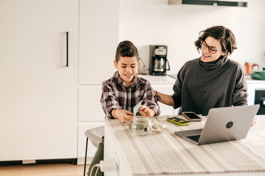 An adult and child working on finances at home. An adult and child working on finances at home.