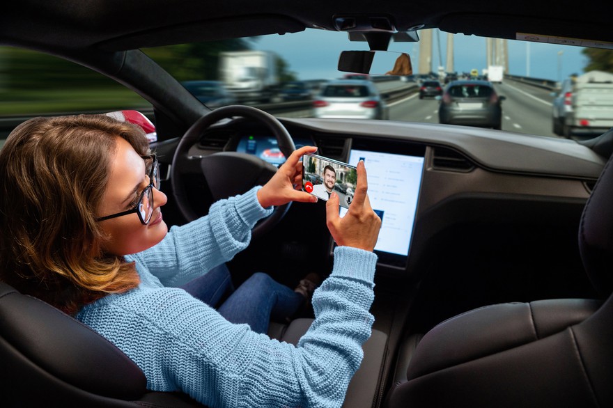Someone using a smartphone in a self-driving car. Someone using a smartphone in a self-driving car.