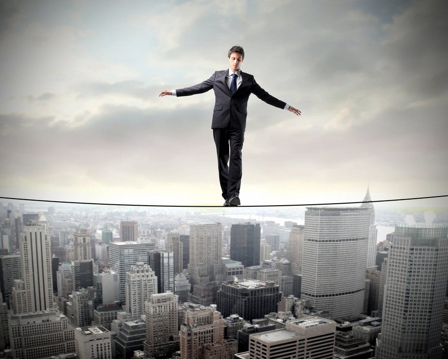 Business man in suit balances on a tightrope above a cloudy city Business man in suit balances on a tightrope above a cloudy city