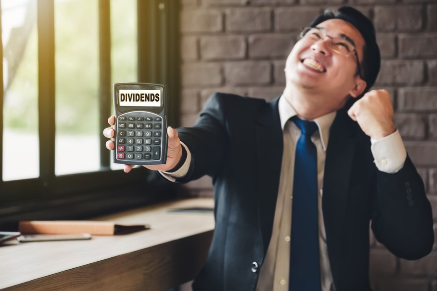 Happy person fist holding a calculator reading "dividends"
