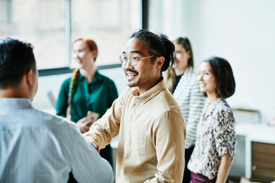 Co-workers shaking hands in conference room. Co-workers shaking hands in conference room.